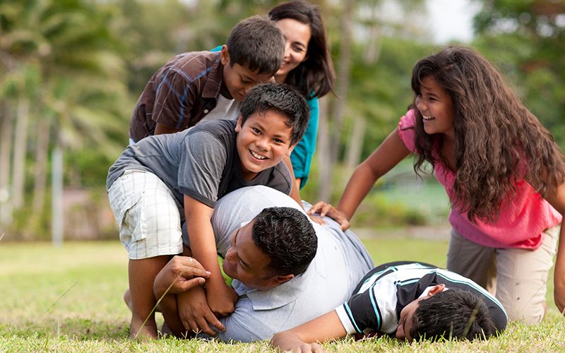 Una famiglia gioca a football in un parco, mettendo in pratica la Parola di Saggezza
