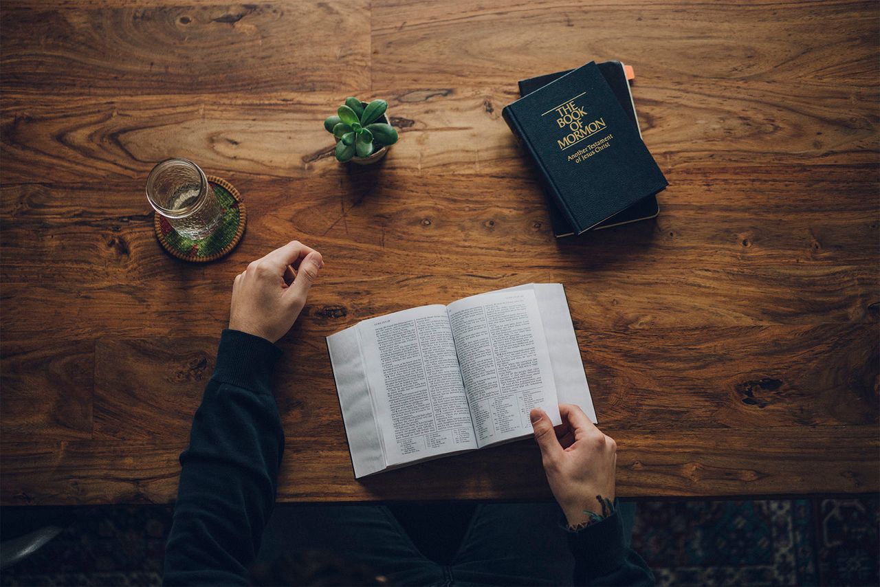Un uomo studia la Bibbia e il Libro di Mormon al tavolo della cucina