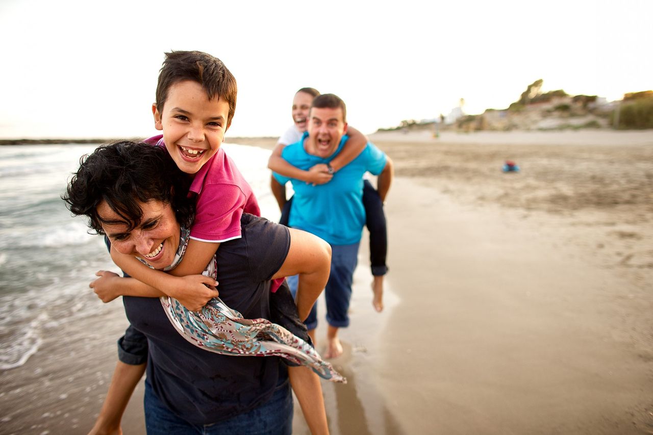 Una famiglia corre e gioca su una spiaggia godendo della compagnia reciproca