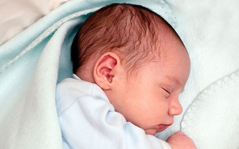 Un neonato che dorme avvolto in una coperta