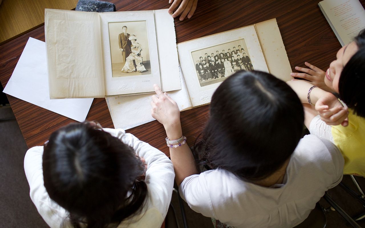 Una famiglia lavora insieme sulla storia familiare guardando un album di foto e ritagli